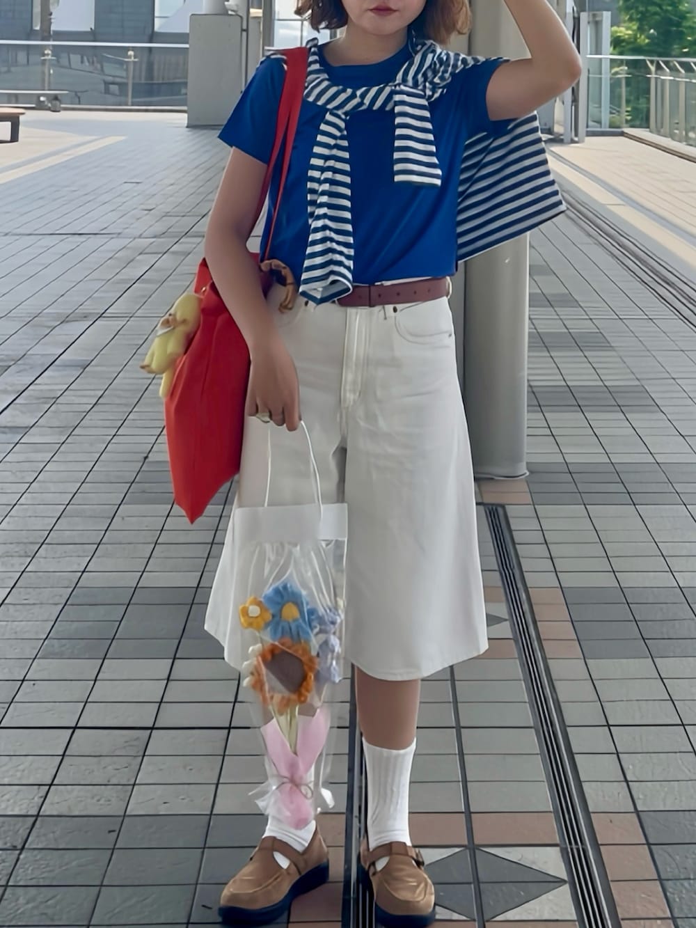 オレンジ系のトートバッグ、ブルー系のTシャツ/カットソー、ホワイト系のデニムパンツを着用したレディースの夏コーディネートの3枚目の写真