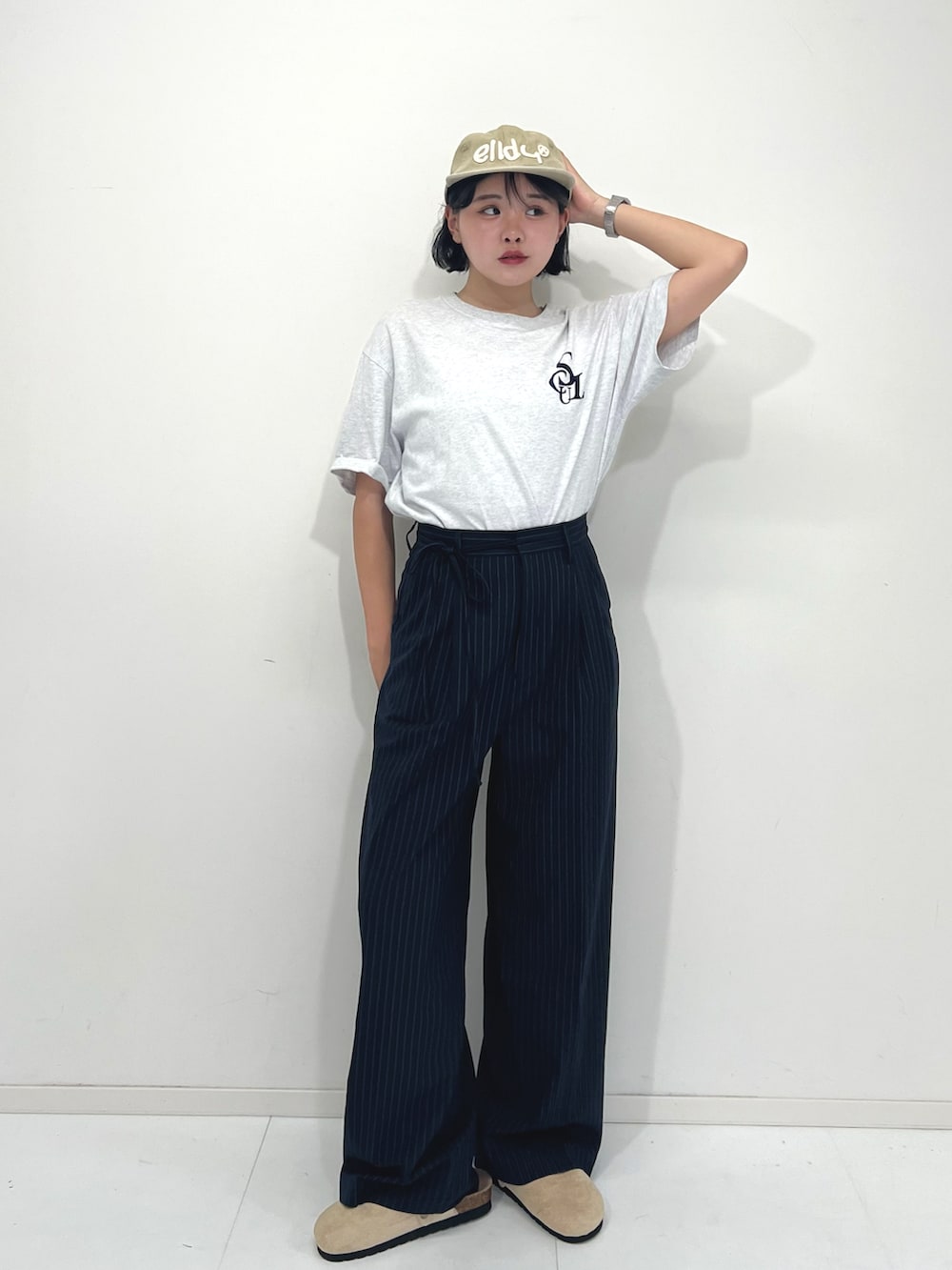 ブルー系のスラックス、ベージュ系のサンダル、ホワイト系のTシャツ/カットソーを着用したレディースの夏コーディネートの2枚目の写真