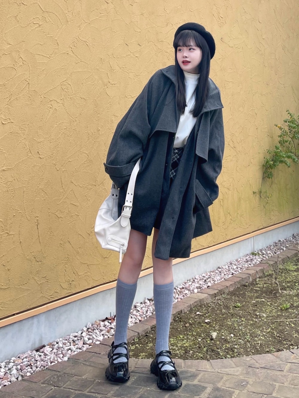 グレー系のトレンチコート、ブラック系のスカート、ブラック系のパンプスを着用したレディースの秋コーディネートの2枚目の写真