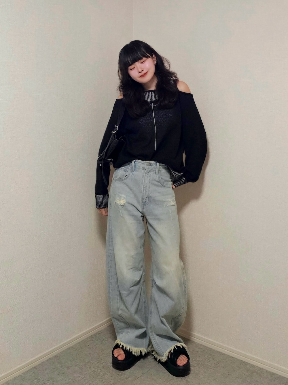 ブラック系のサンダル、ブラック系のニット/セーター、ブルー系のデニムパンツを着用したレディースの春コーディネートの2枚目の写真