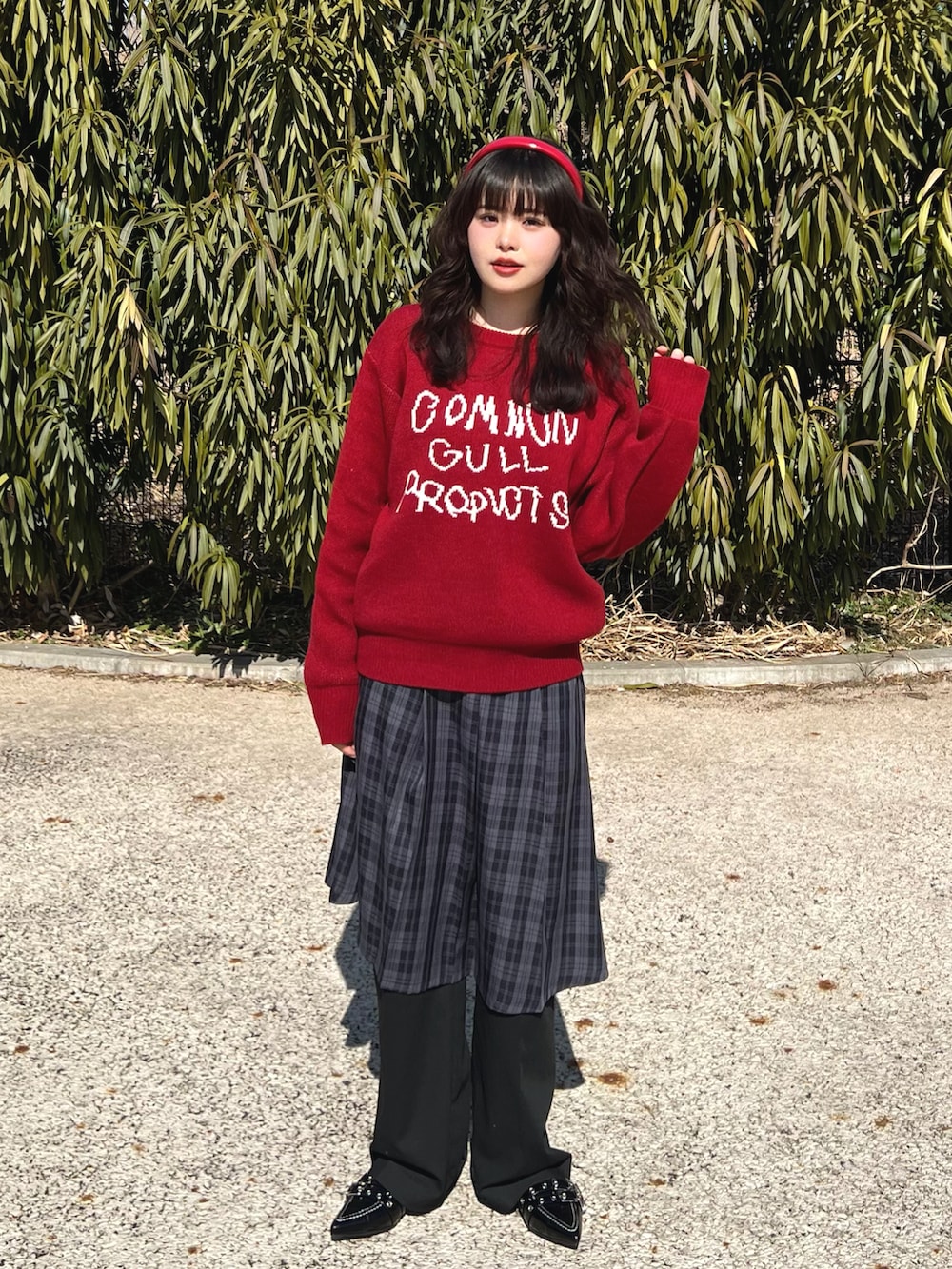 レッド系のニット/セーター、ブラック系のスカート、ブラック系のスラックスを着用したレディースの春コーディネートの2枚目の写真