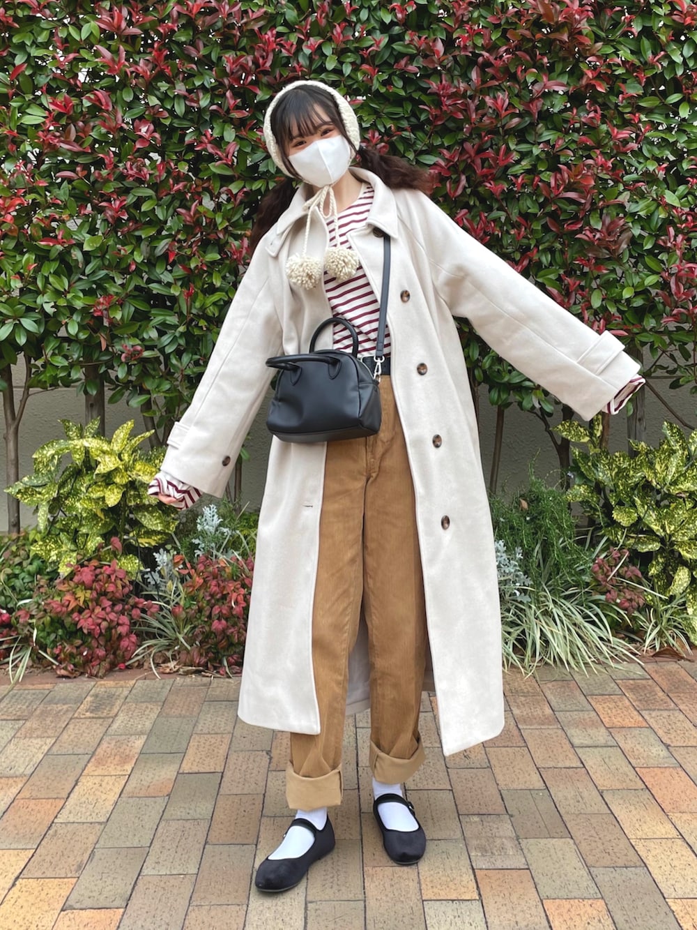 ホワイト系のステンカラーコート、レッド系のTシャツ/カットソー、ブラック系のボストンバッグを着用したレディースの冬コーディネートの3枚目の写真