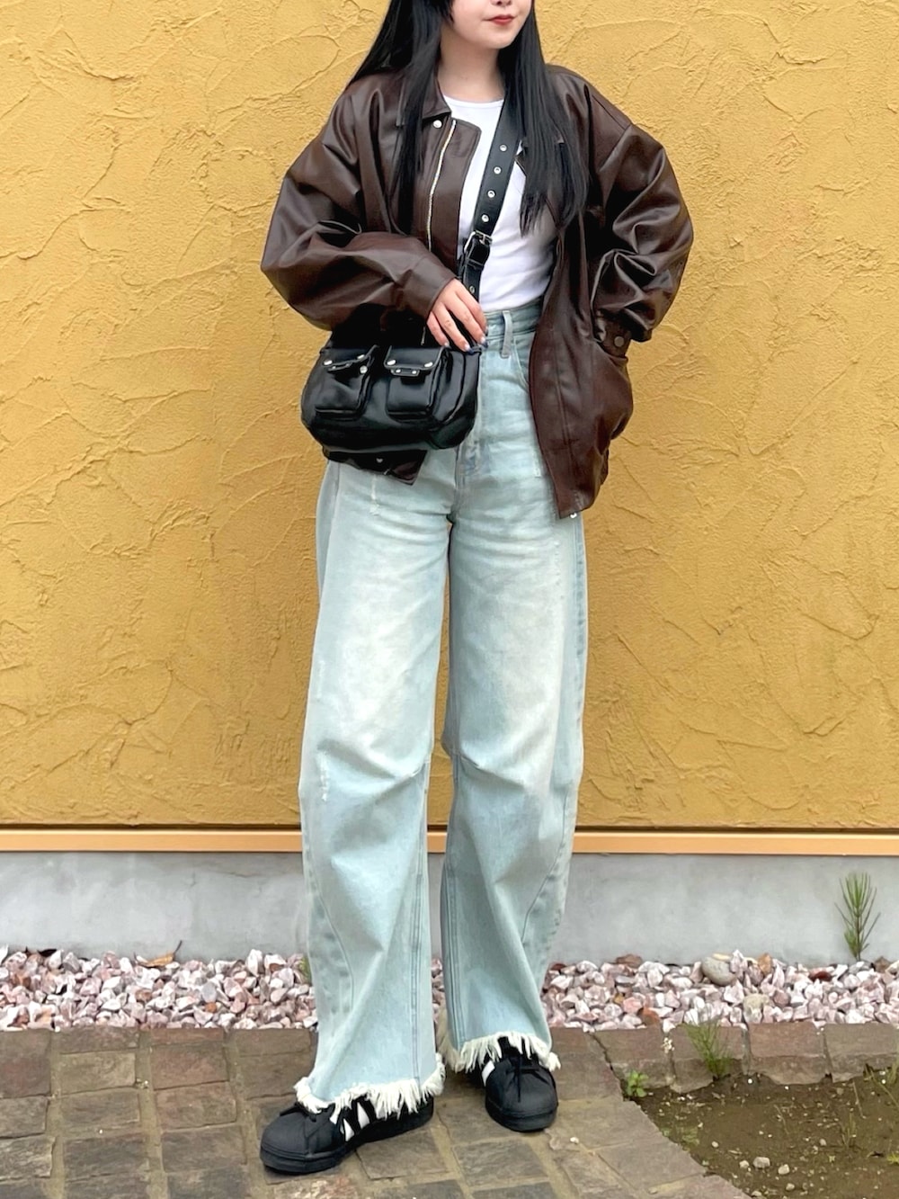 ブラウン系のライダースジャケット、ホワイト系のTシャツ/カットソー、ブルー系のデニムパンツを着用したレディースの春コーディネートの3枚目の写真