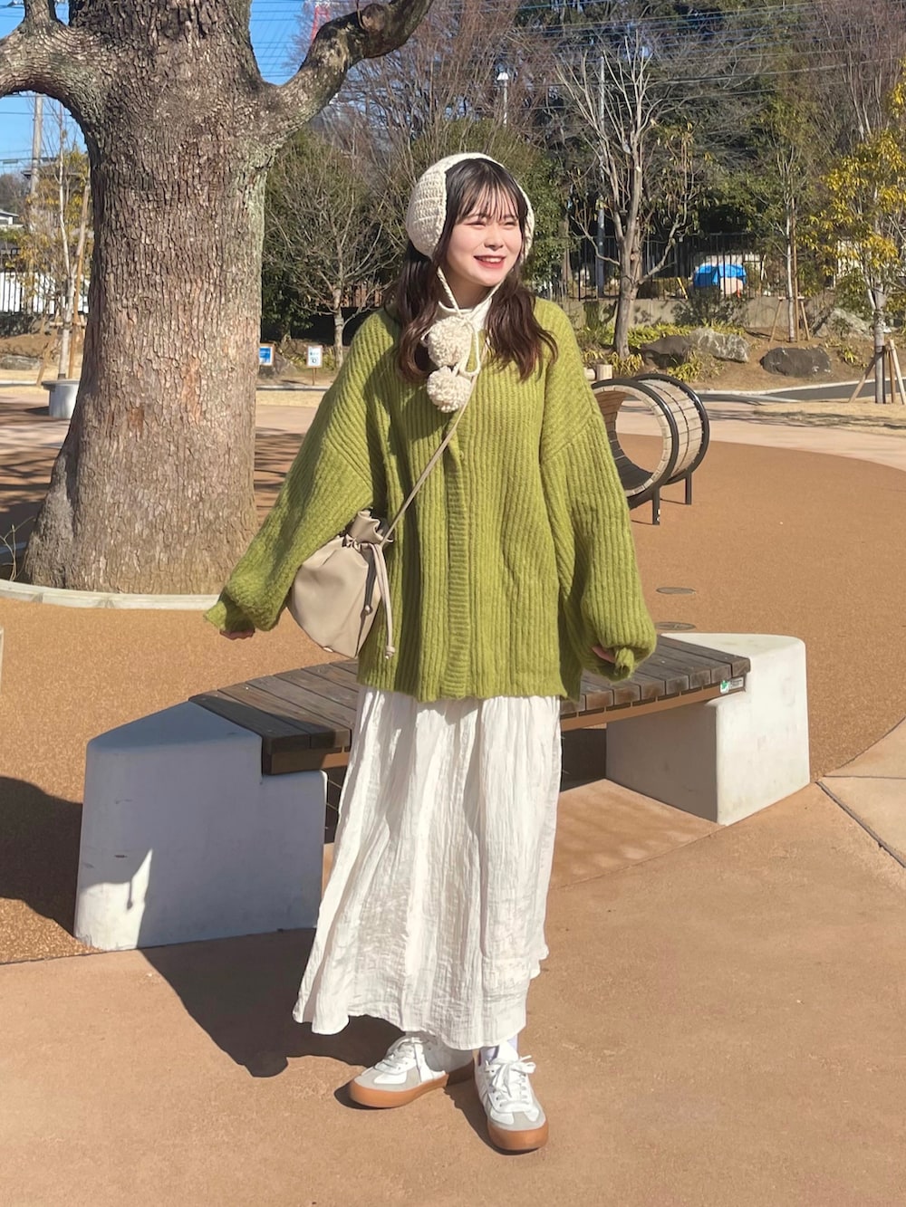 ホワイト系のスニーカー、ホワイト系のスカート、ブラウン系のショルダーバッグを着用したレディースの冬コーディネートの2枚目の写真