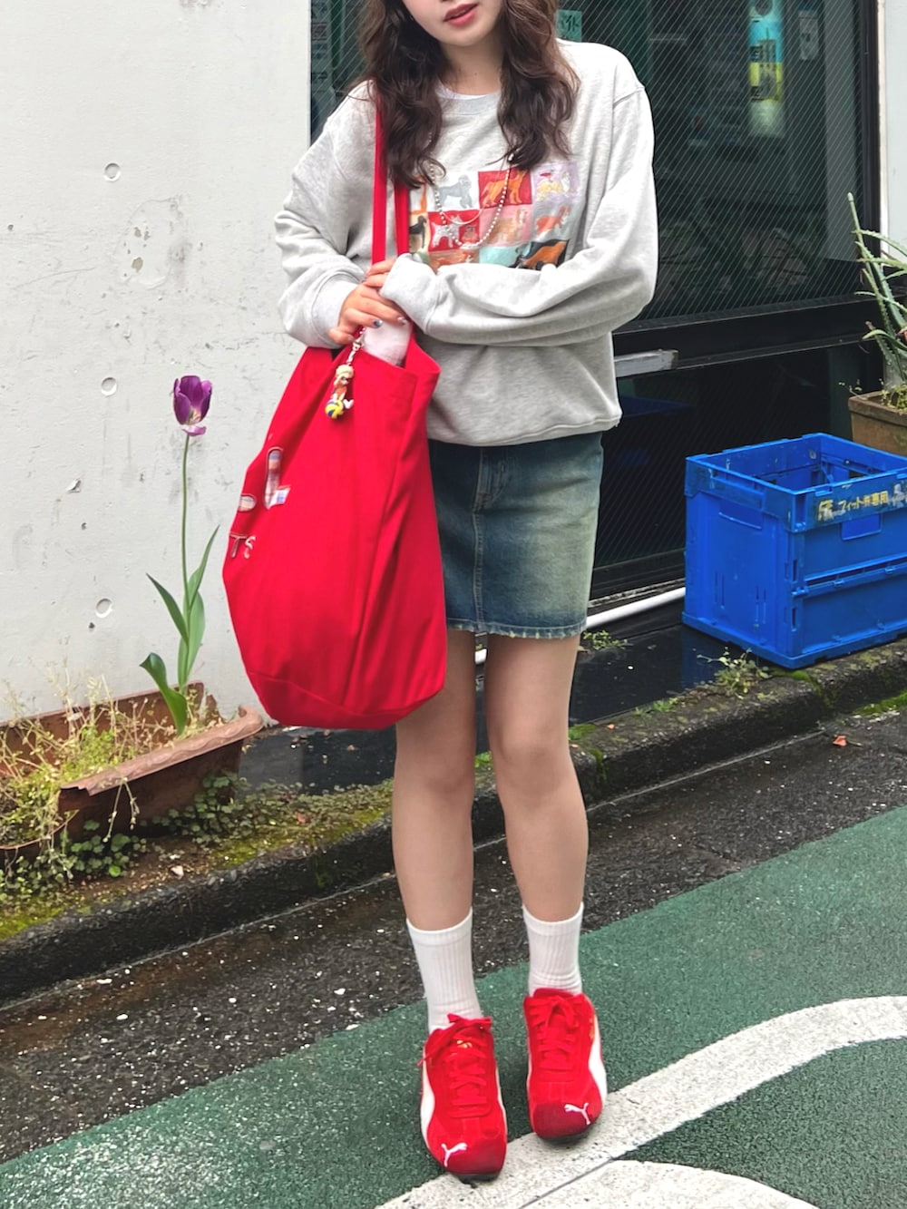 レッド系のバッグ、ホワイト系のスウェット、ブルー系のデニムスカートを着用したレディースの春コーディネートの3枚目の写真
