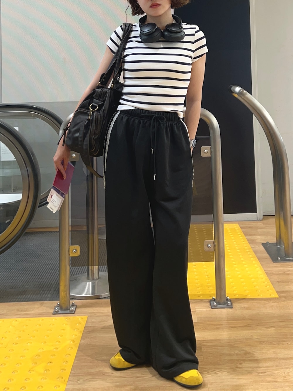 ブラック系のその他パンツ、イエロー系のスニーカー、ホワイト系のTシャツ/カットソーを着用したレディースの秋コーディネートの3枚目の写真