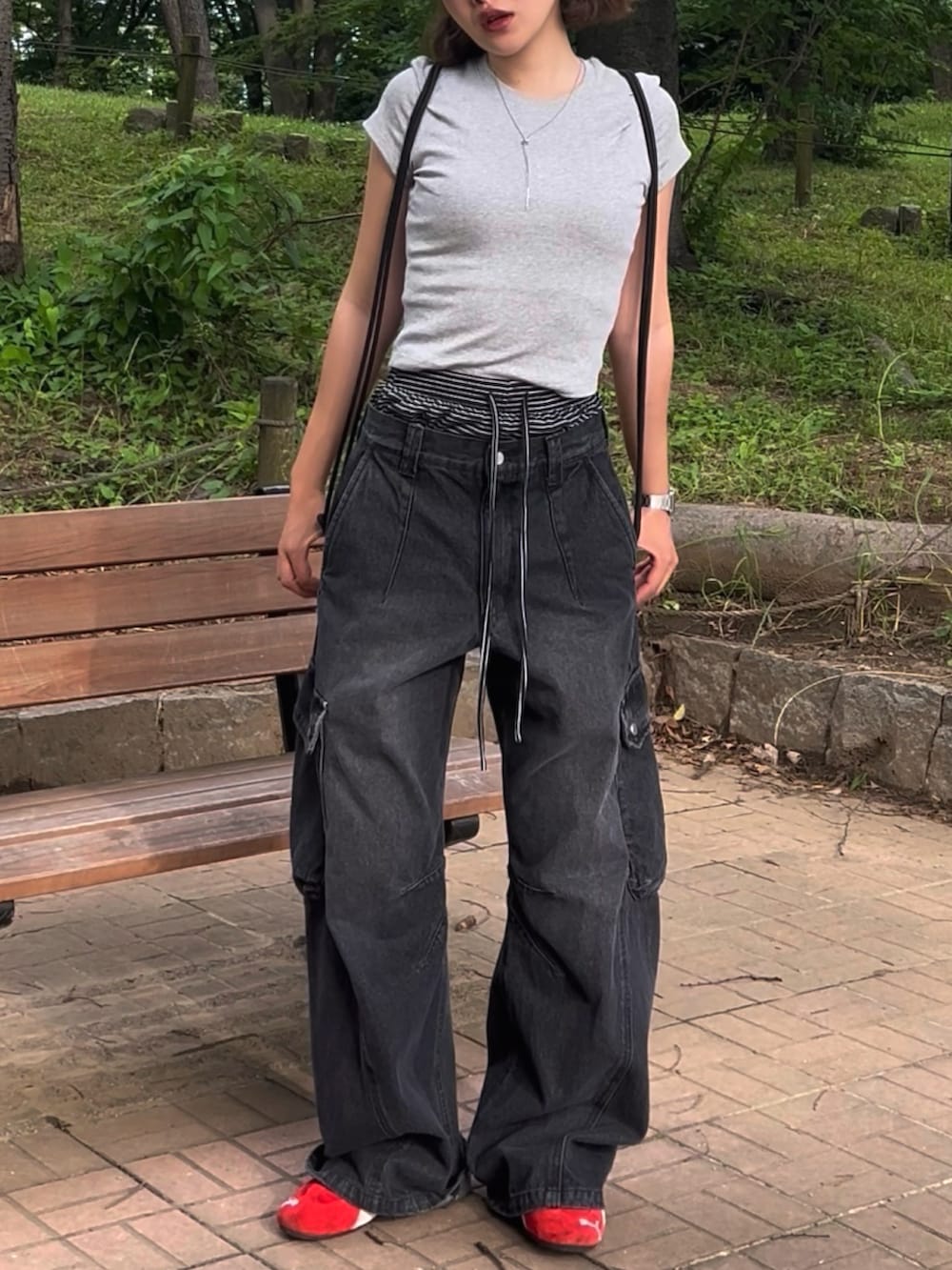 グレー系のTシャツ/カットソー、ブラック系のデニムパンツ、レッド系のスニーカーを着用したレディースの夏コーディネートの3枚目の写真