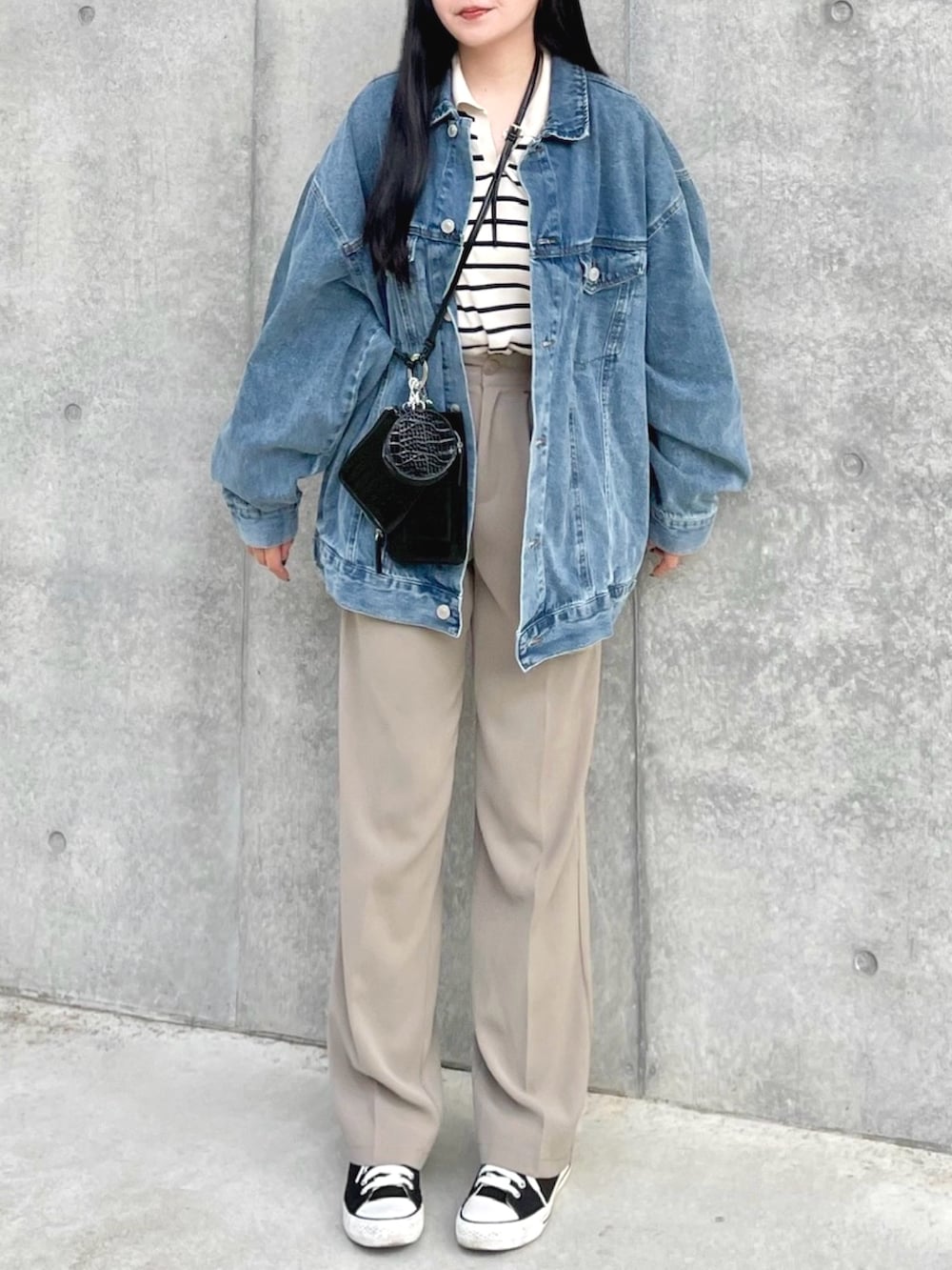 ブルー系のデニムジャケット、ベージュ系のニット/セーター、ベージュ系のスラックスを着用したレディースの春コーディネートの3枚目の写真