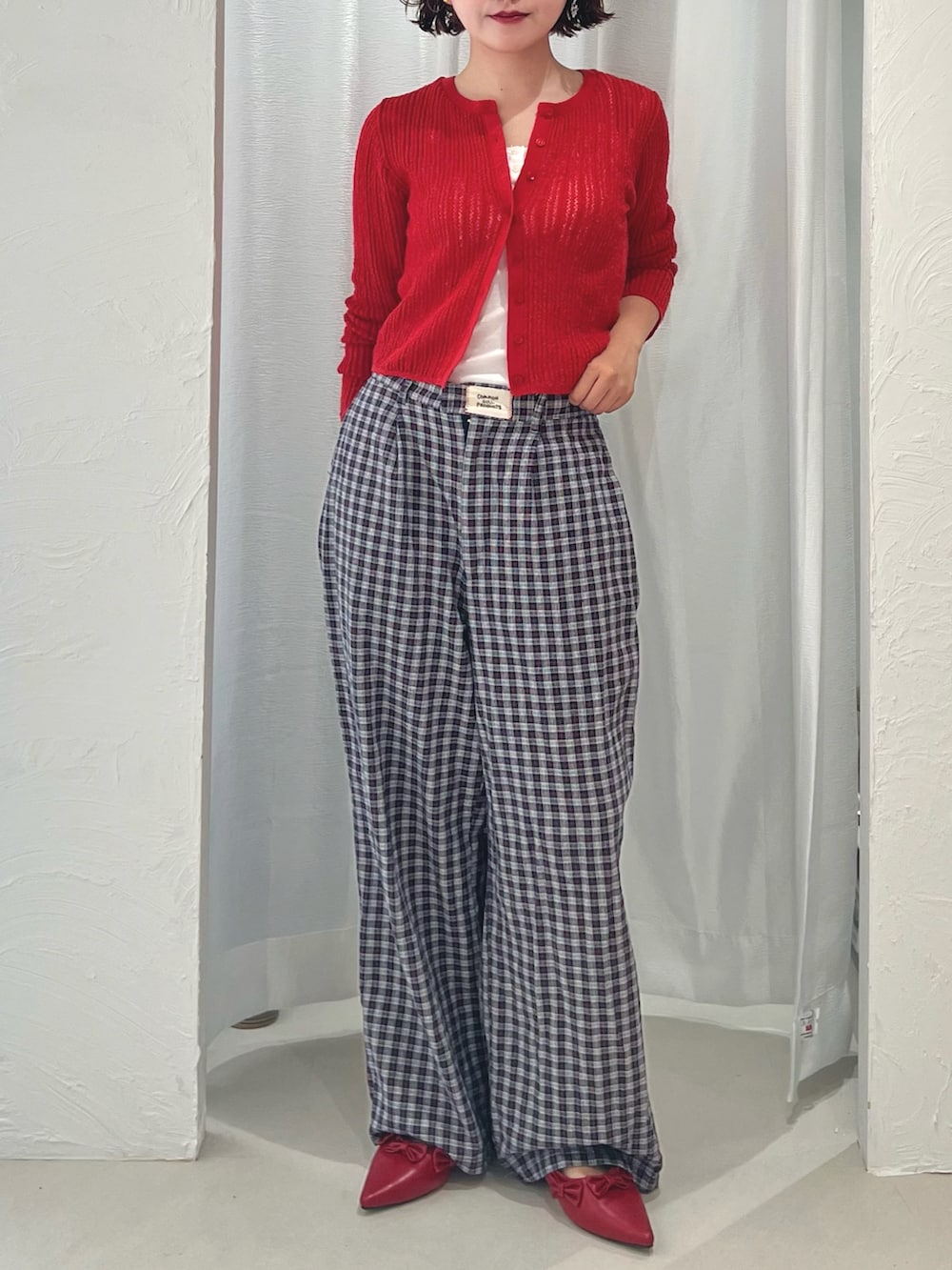 ホワイト系のキャミソール、レッド系のパンプス、ブルー系のスラックスを着用したレディースの秋コーディネートの3枚目の写真