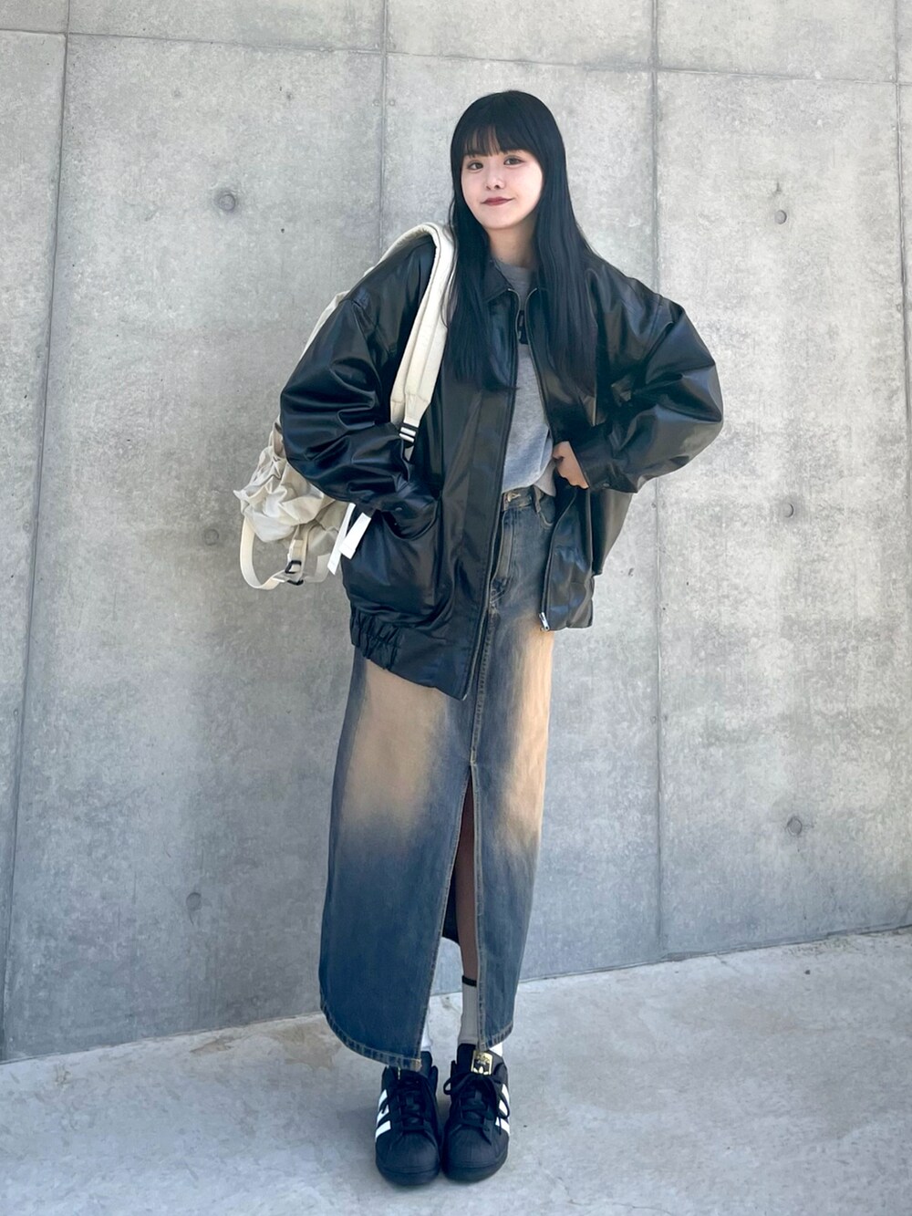 ブラック系のブルゾン、グレー系のスウェット、ブルー系のデニムスカートを着用したレディースの春コーディネートの2枚目の写真