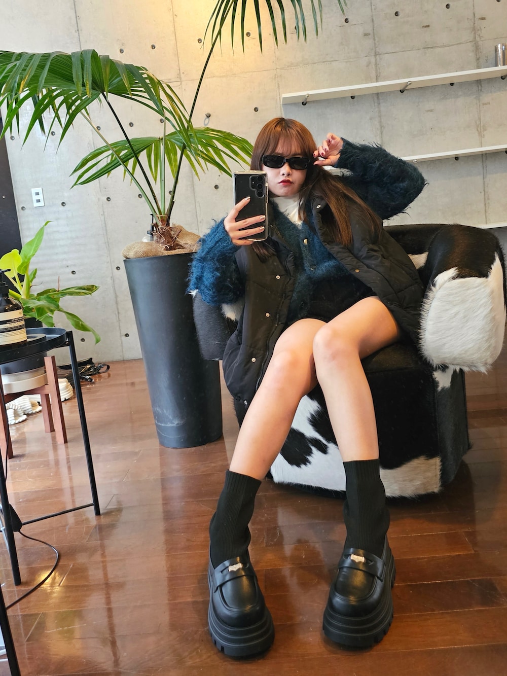 ブラック系のブーツ、ブルー系のカーディガン/ボレロ、ブラック系のダウンベストを着用したレディースの秋コーディネートの2枚目の写真