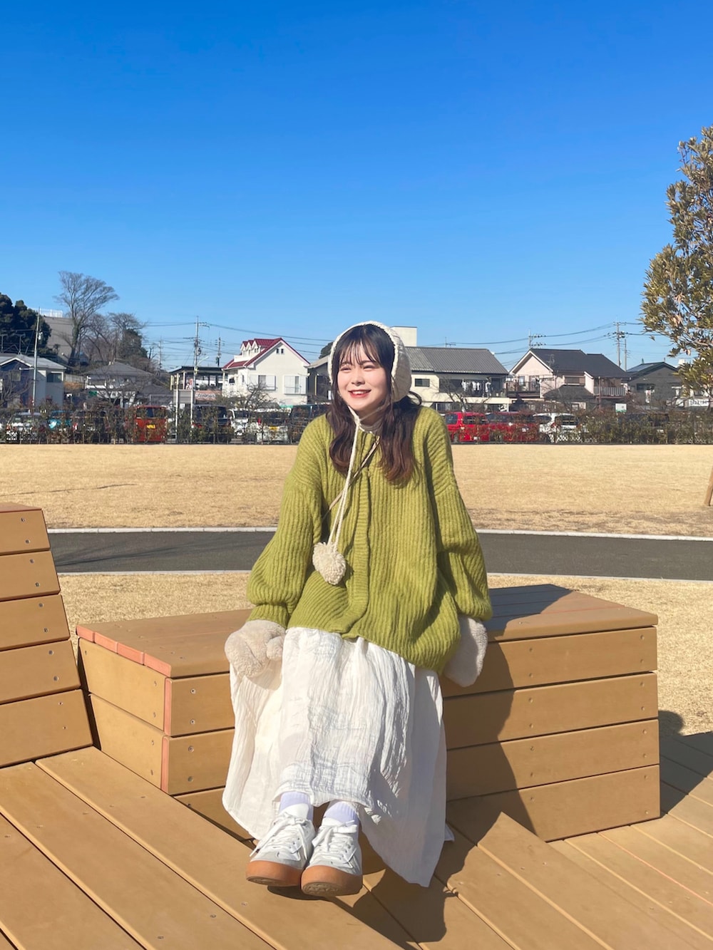 ホワイト系のスニーカー、ホワイト系のスカート、ブラウン系のショルダーバッグを着用したレディースの冬コーディネートの3枚目の写真