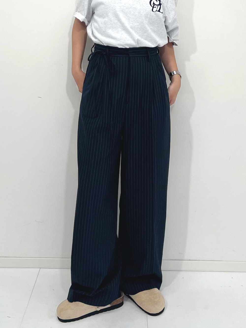 ブルー系のスラックス、ベージュ系のサンダル、ホワイト系のTシャツ/カットソーを着用したレディースの夏コーディネートの4枚目の写真