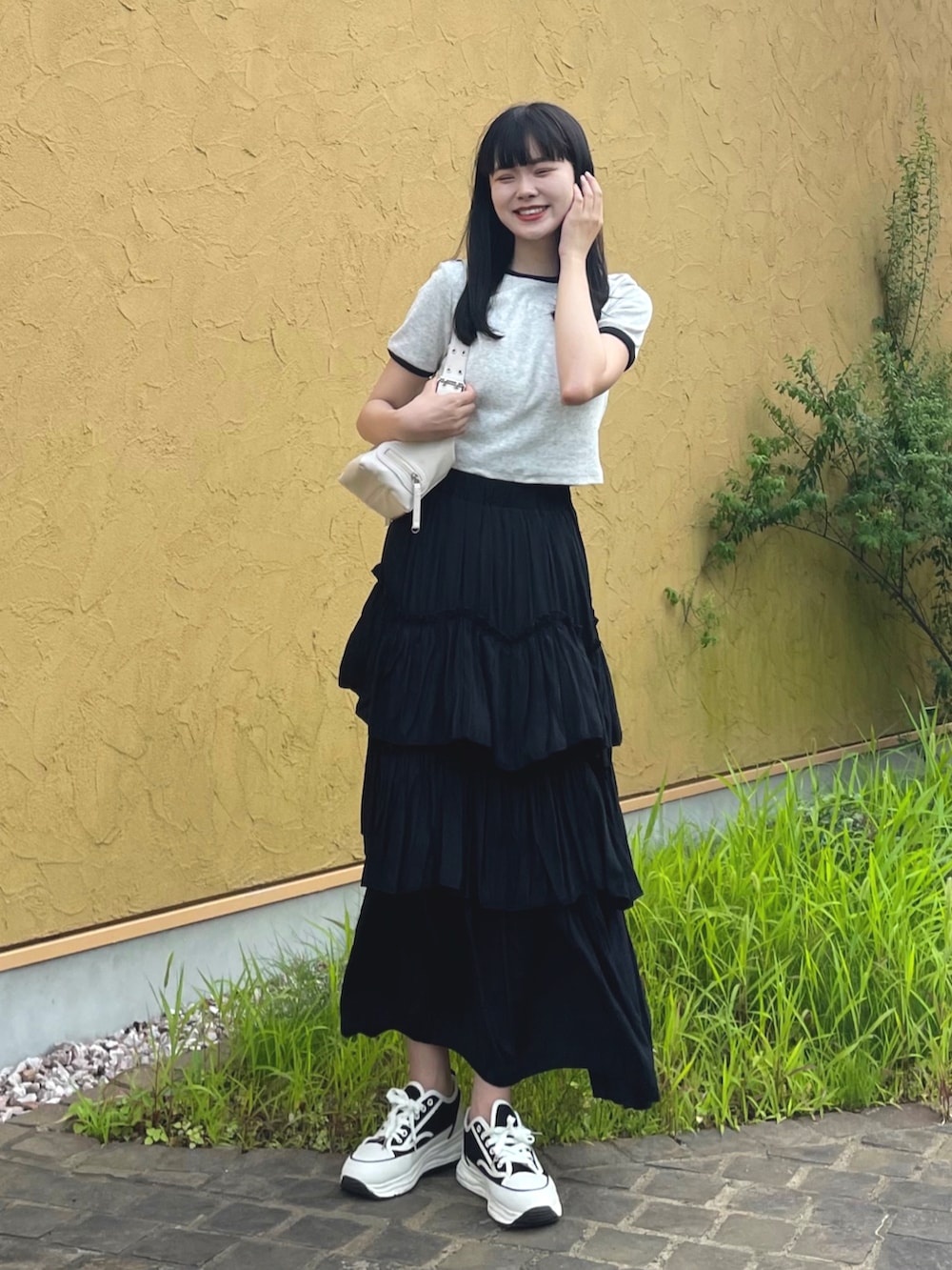 グレー系のTシャツ/カットソー、ブラック系のスカート、ホワイト系のショルダーバッグを着用したレディースの夏コーディネートの2枚目の写真