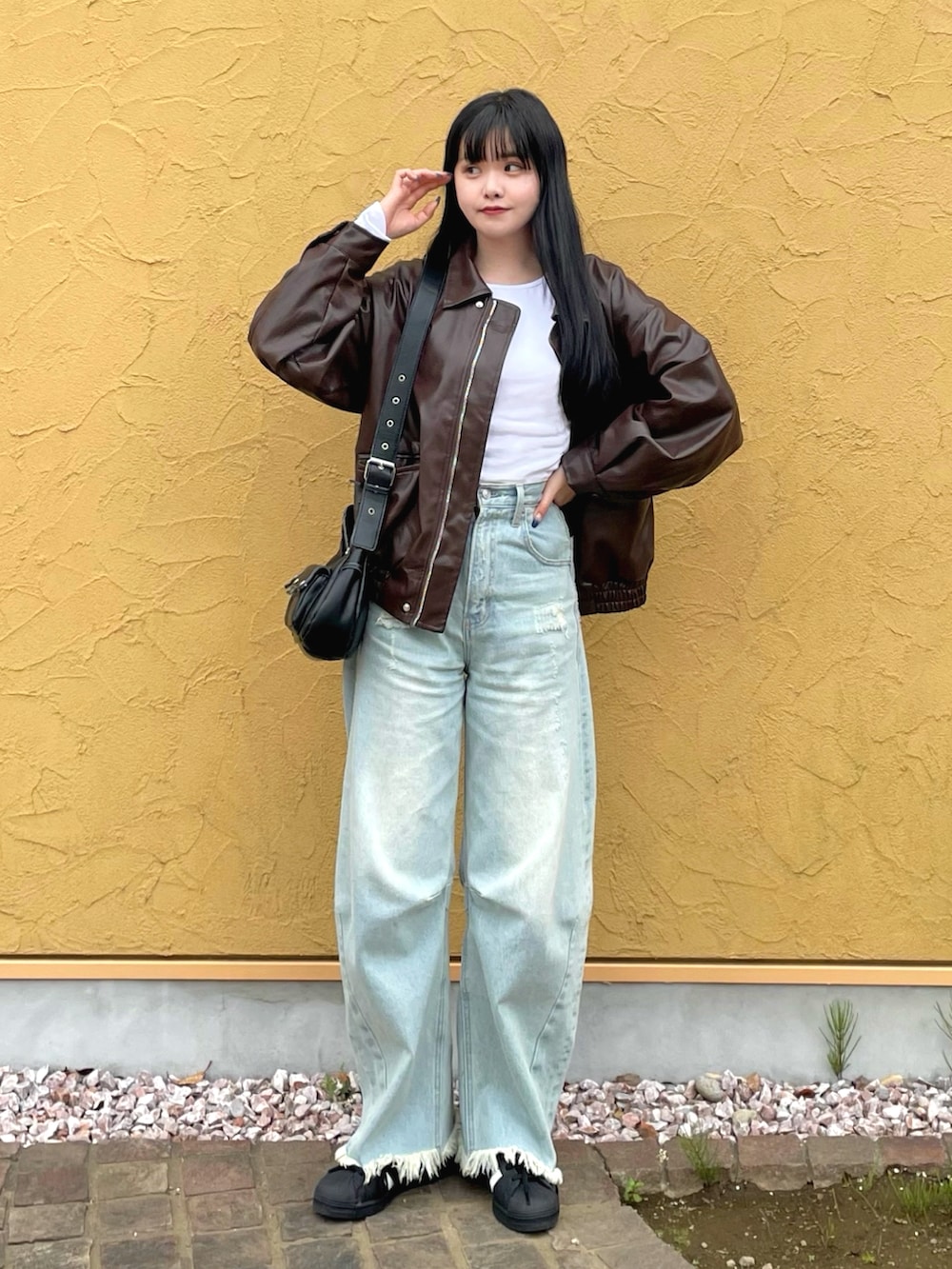 ブラウン系のライダースジャケット、ホワイト系のTシャツ/カットソー、ブルー系のデニムパンツを着用したレディースの春コーディネートの2枚目の写真