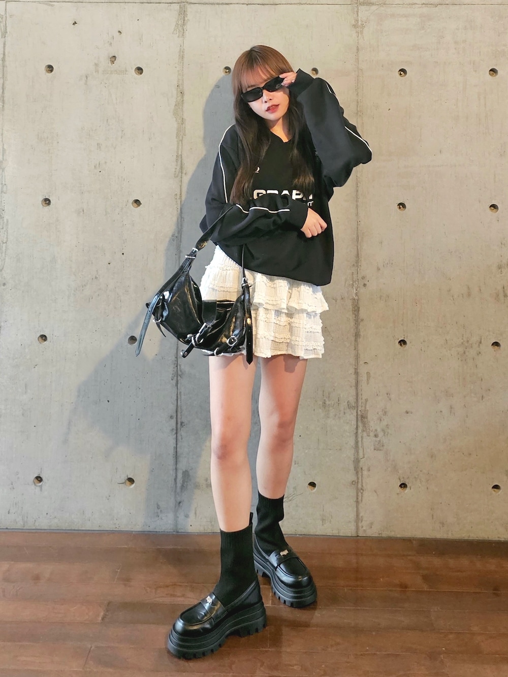 ブラック系のスウェット、ホワイト系のスカート、ブラック系のショルダーバッグを着用したレディースの秋コーディネートの4枚目の写真