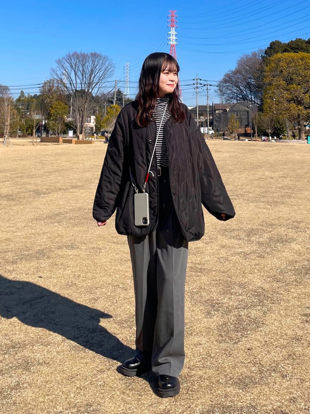 グレー系のスラックス、ブラック系のブーツ、ブラック系のノーカラージャケットを着用したレディースの冬コーディネートの2枚目の写真