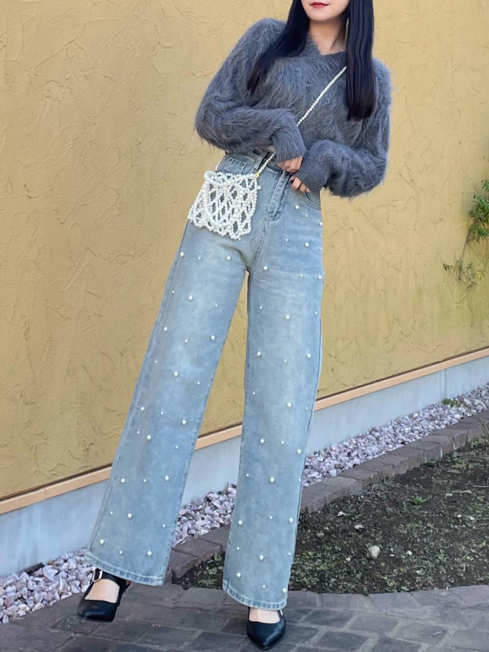 グレー系のニット/セーター、ホワイト系のキャミソール、ブルー系のデニムパンツを着用したレディースの秋コーディネートの3枚目の写真