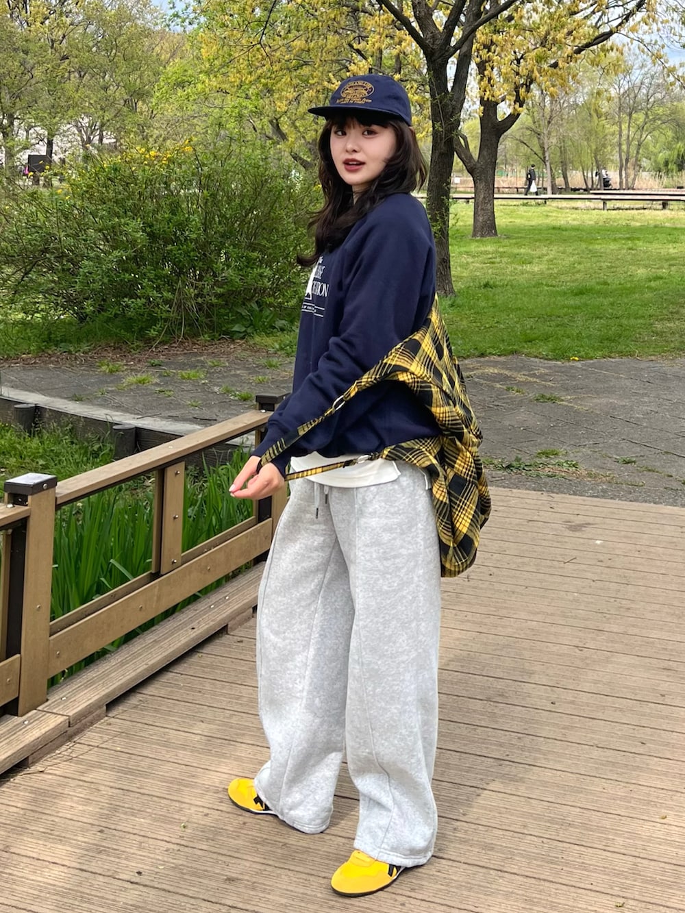 ブルー系のスウェット、グレー系のスウェットパンツ、イエロー系のスニーカーを着用したレディースの春コーディネートの2枚目の写真