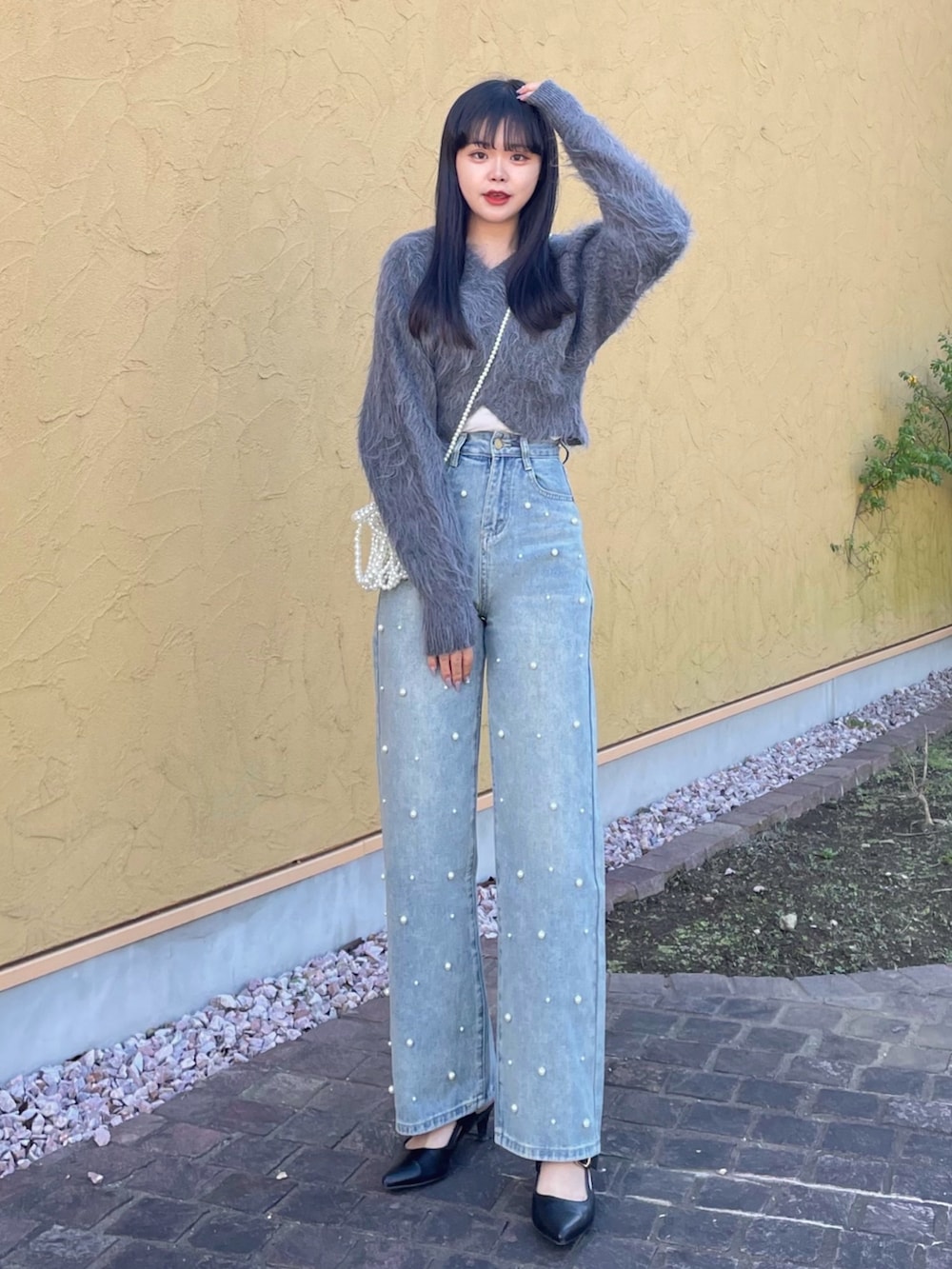 グレー系のニット/セーター、ホワイト系のキャミソール、ブルー系のデニムパンツを着用したレディースの秋コーディネートの2枚目の写真