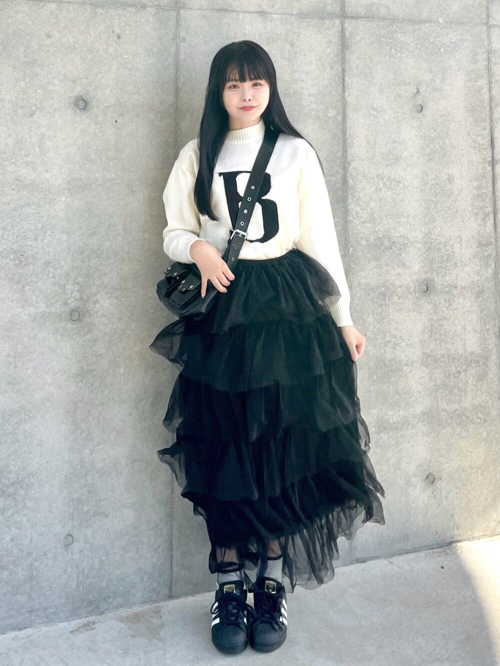 ホワイト系のニット/セーター、ブラック系のスカート、ブラック系のスニーカーを着用したレディースの春コーディネートの2枚目の写真