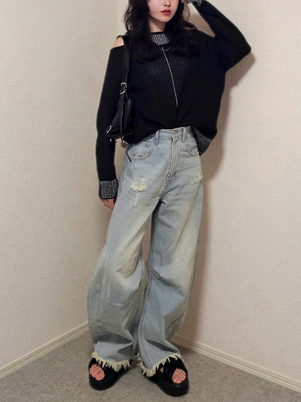 ブラック系のサンダル、ブラック系のニット/セーター、ブルー系のデニムパンツを着用したレディースの春コーディネートの3枚目の写真