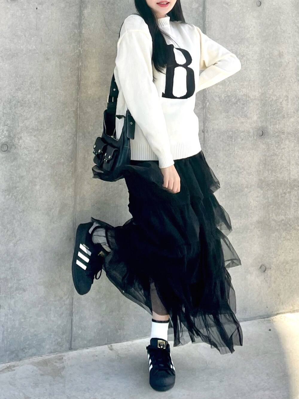 ホワイト系のニット/セーター、ブラック系のスカート、ブラック系のスニーカーを着用したレディースの春コーディネートの3枚目の写真
