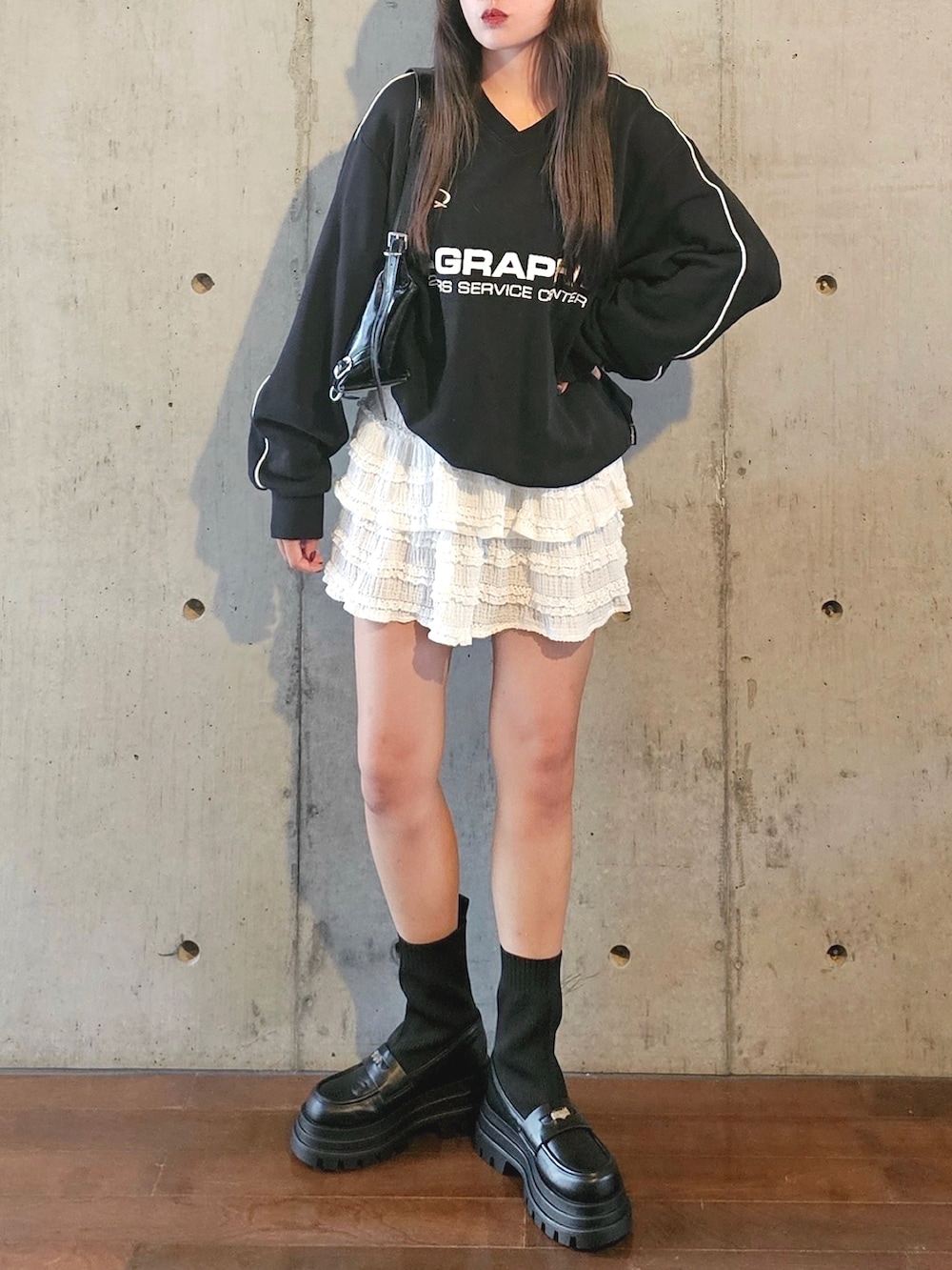 ブラック系のスウェット、ホワイト系のスカート、ブラック系のショルダーバッグを着用したレディースの秋コーディネートの5枚目の写真