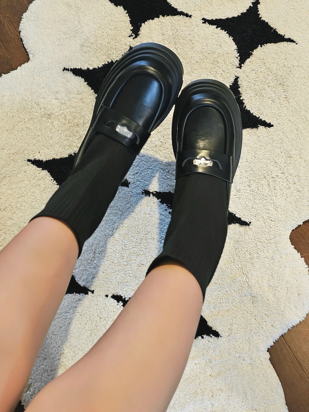 ブラック系のスウェット、ホワイト系のスカート、ブラック系のショルダーバッグを着用したレディースの秋コーディネートの2枚目の写真