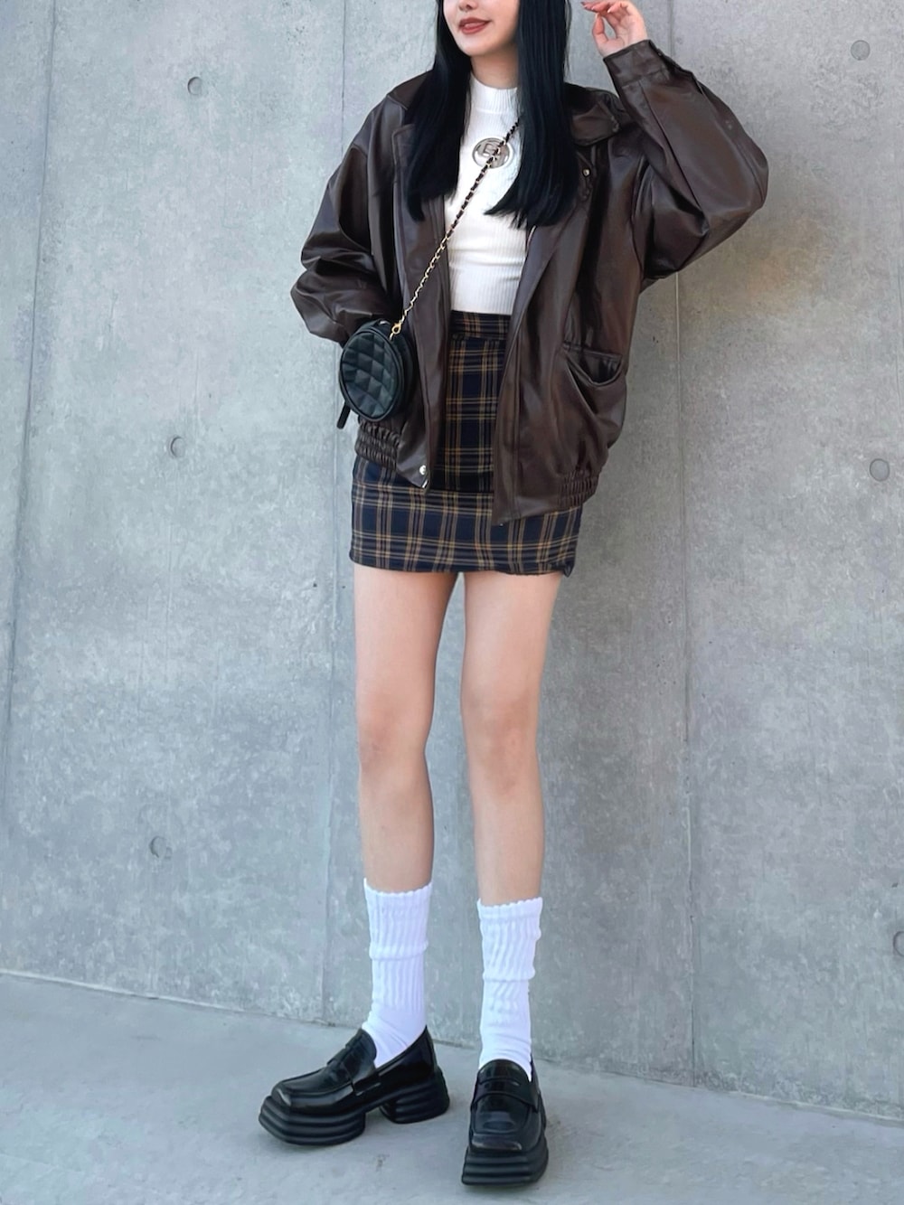 ブラウン系のライダースジャケット、ホワイト系のニット/セーター、ブルー系のスカートを着用したレディースの冬コーディネートの3枚目の写真