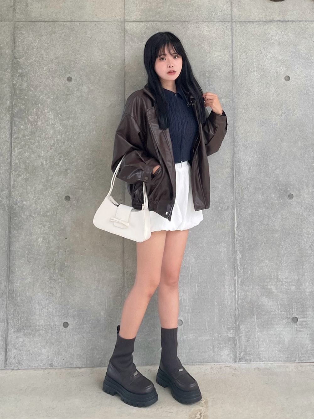 ブラウン系のブーツ、ブラウン系のライダースジャケット、ブルー系のニット/セーターを着用したレディースの秋コーディネートの2枚目の写真