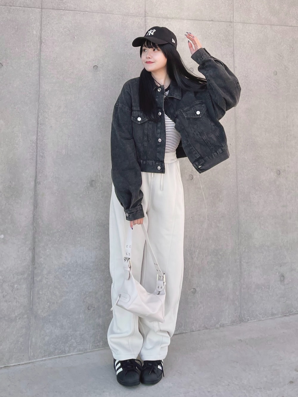 ブラック系のデニムジャケット、ブラック系のTシャツ/カットソー、ホワイト系のショルダーバッグを着用したレディースの春コーディネートの2枚目の写真