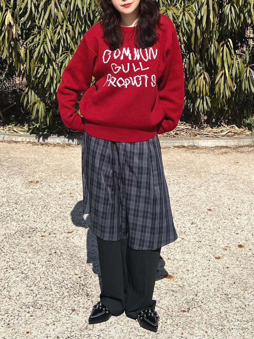 レッド系のニット/セーター、ブラック系のスカート、ブラック系のスラックスを着用したレディースの春コーディネートの3枚目の写真