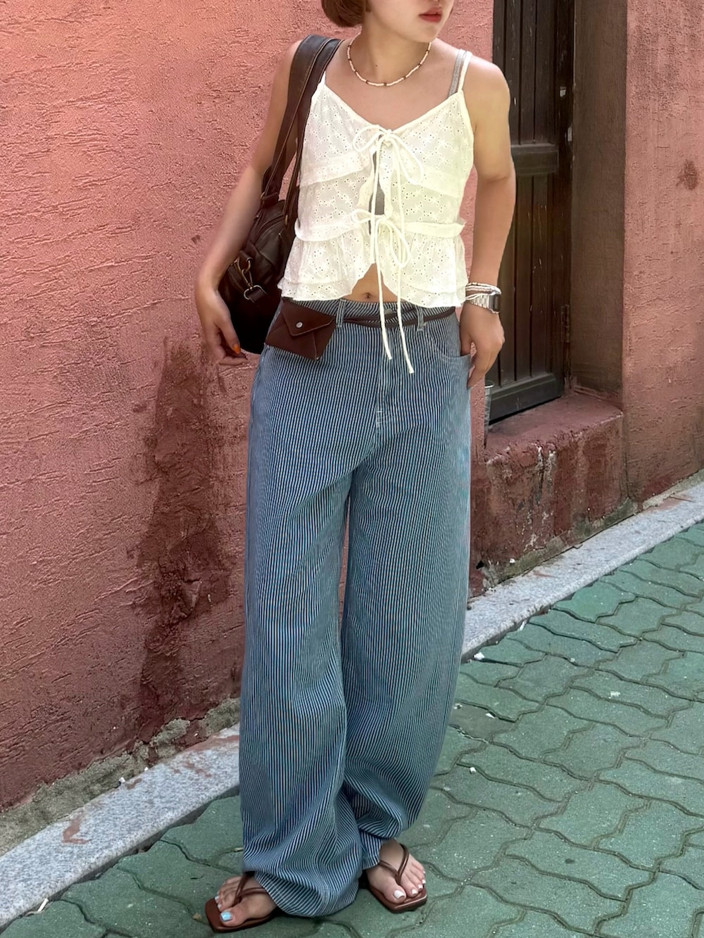 ブラウン系のボストンバッグ、ブラウン系のサンダル、ホワイト系のキャミソールを着用したレディースの夏コーディネートの3枚目の写真