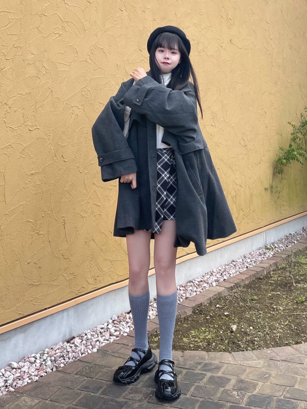 グレー系のトレンチコート、ブラック系のスカート、ブラック系のパンプスを着用したレディースの秋コーディネートの3枚目の写真