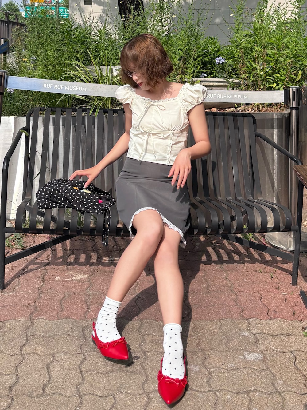 ホワイト系のシャツ/ブラウス、グレー系のスカート、レッド系のパンプスを着用したレディースの夏コーディネートの2枚目の写真