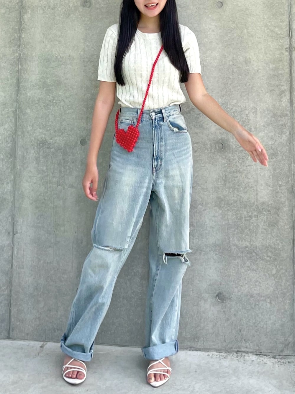 ホワイト系のニット/セーター、ブルー系のデニムパンツ、レッド系のショルダーバッグを着用したレディースの夏コーディネートの3枚目の写真