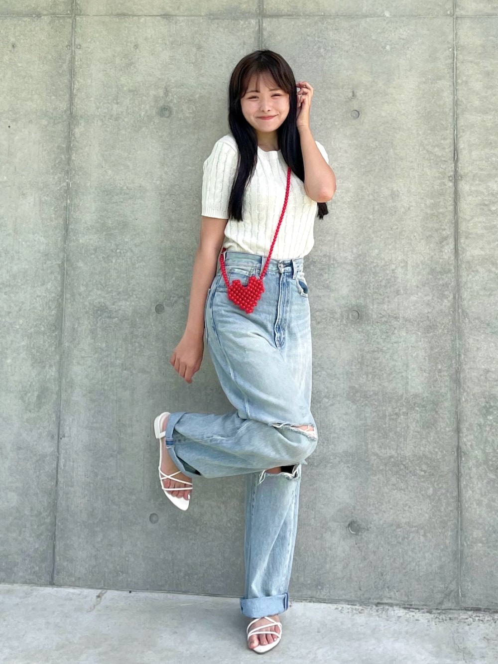 ホワイト系のニット/セーター、ブルー系のデニムパンツ、レッド系のショルダーバッグを着用したレディースの夏コーディネートの2枚目の写真