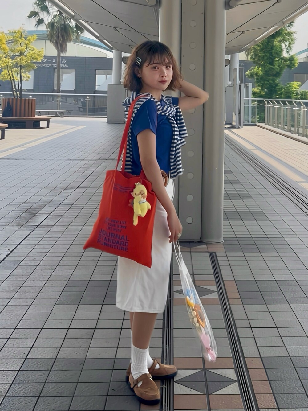 オレンジ系のトートバッグ、ブルー系のTシャツ/カットソー、ホワイト系のデニムパンツを着用したレディースの夏コーディネートの2枚目の写真