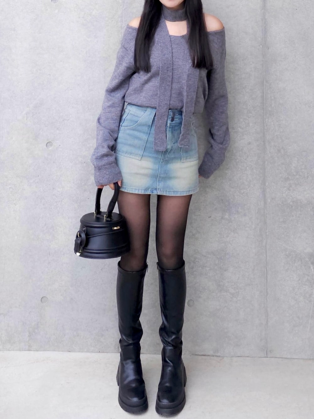 グレー系のニット/セーター、ブルー系のデニムスカート、ブラック系のブーツを着用したレディースの秋コーディネートの3枚目の写真