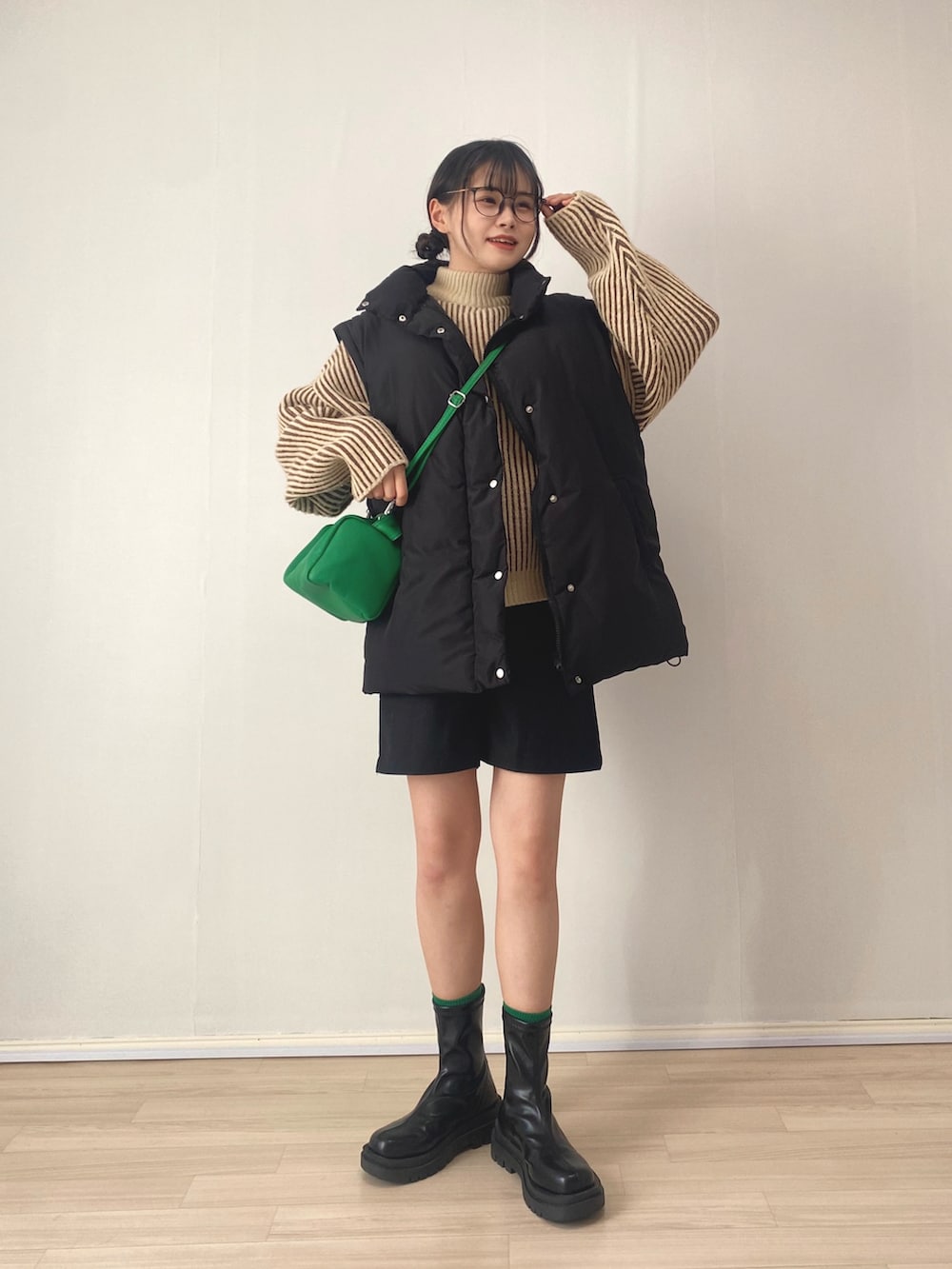 ブラック系のダウンジャケット/コート、ブラウン系のニット/セーター、グリーン系のショルダーバッグを着用したレディースの冬コーディネートの2枚目の写真