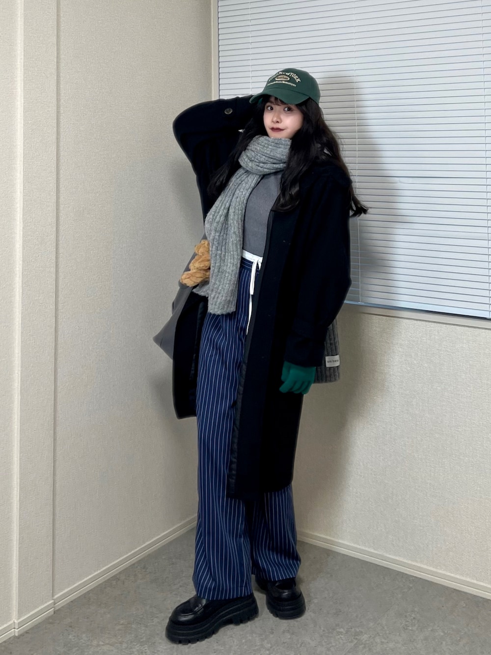 グレー系のニット/セーター、グレー系のショルダーバッグ、ブルー系のスラックスを着用したレディースの冬コーディネートの2枚目の写真