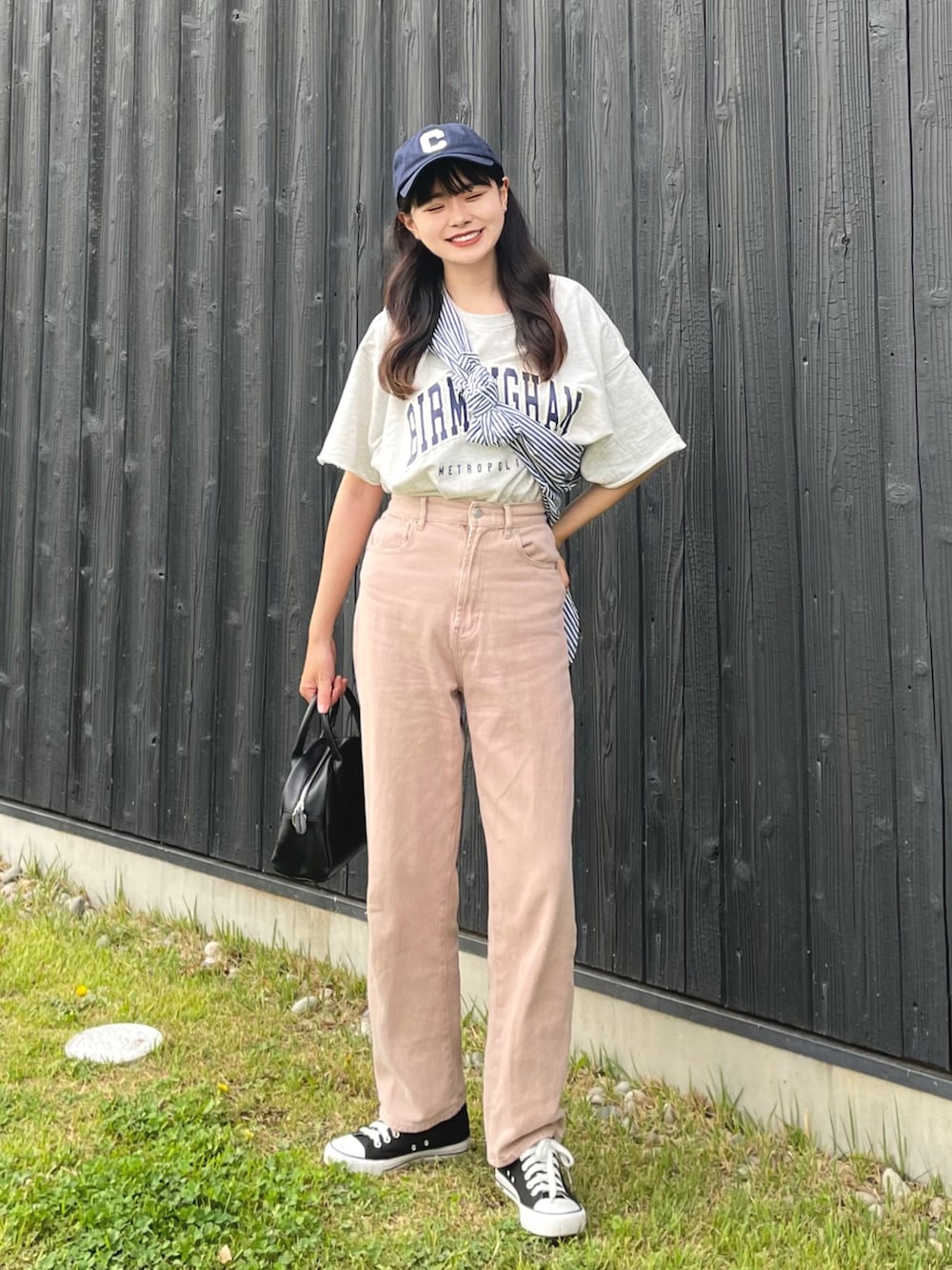 ブラック系のボストンバッグ、ピンク系のデニムパンツ、グレー系のTシャツ/カットソーを着用したレディースの春コーディネートの2枚目の写真