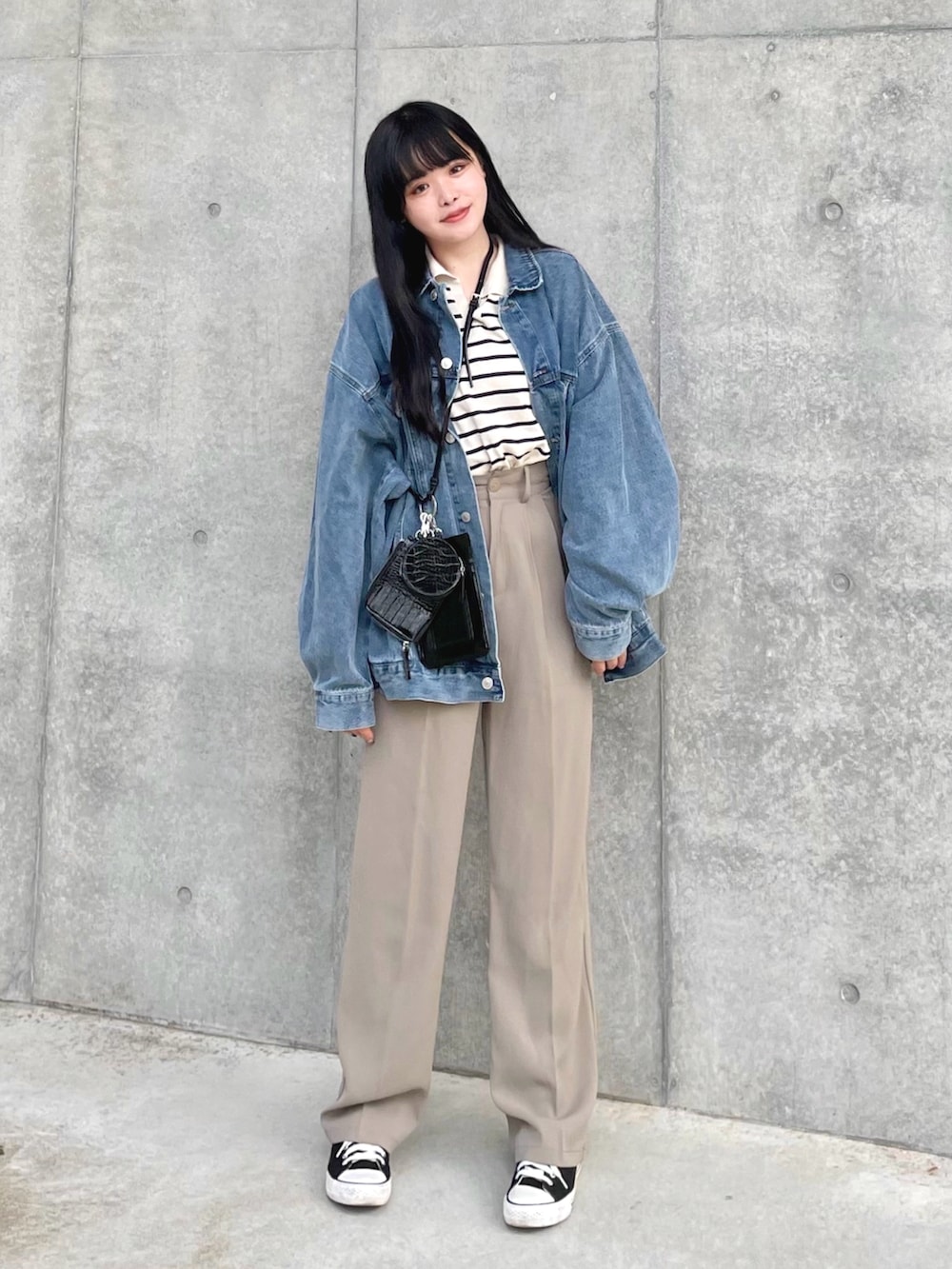 ブルー系のデニムジャケット、ベージュ系のニット/セーター、ベージュ系のスラックスを着用したレディースの春コーディネートの2枚目の写真