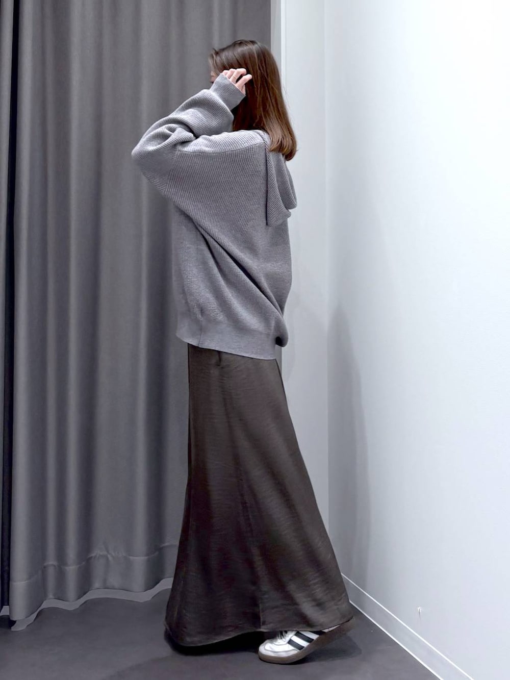 グレー系のスカート、グレー系のニット/セーター、ブラック系のショルダーバッグを着用したレディースの秋コーディネートの3枚目の写真