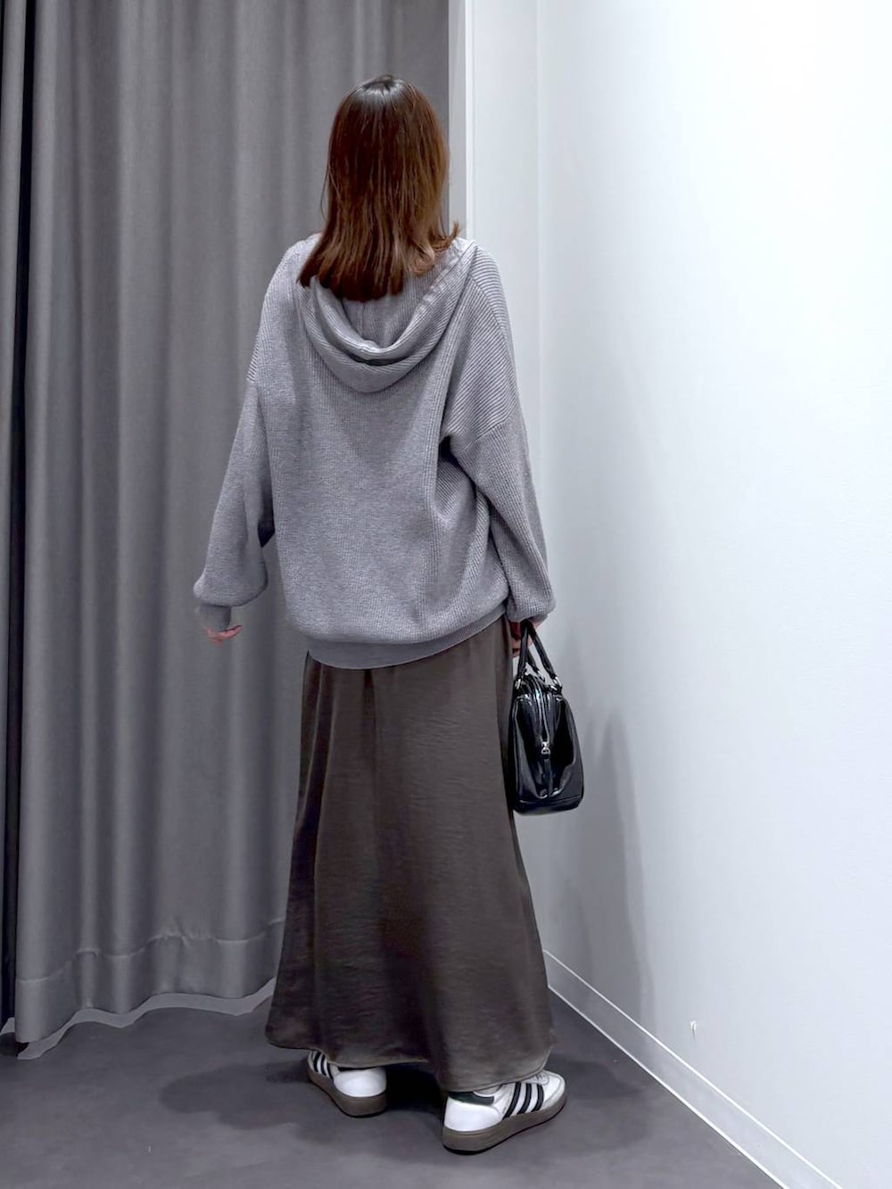 グレー系のスカート、グレー系のニット/セーター、ブラック系のショルダーバッグを着用したレディースの秋コーディネートの4枚目の写真