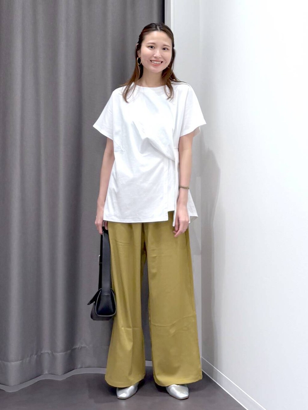 シルバー系のパンプス、ブラック系のショルダーバッグ、ホワイト系のTシャツ/カットソーを着用したレディースの夏コーディネートの2枚目の写真