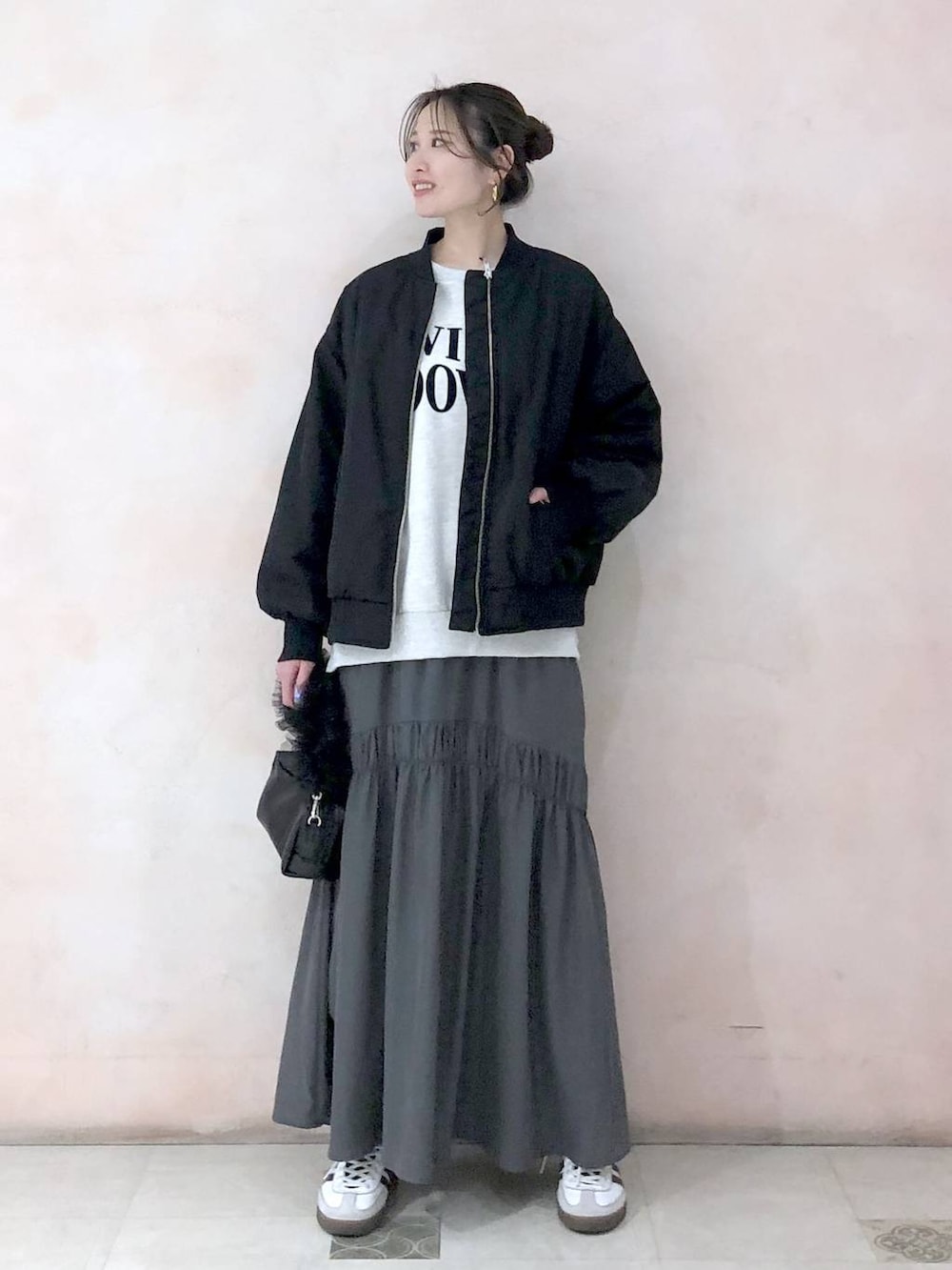ブラック系のMA-1、ベージュ系のスウェット、グレー系のスカートを着用したレディースの冬コーディネートの2枚目の写真