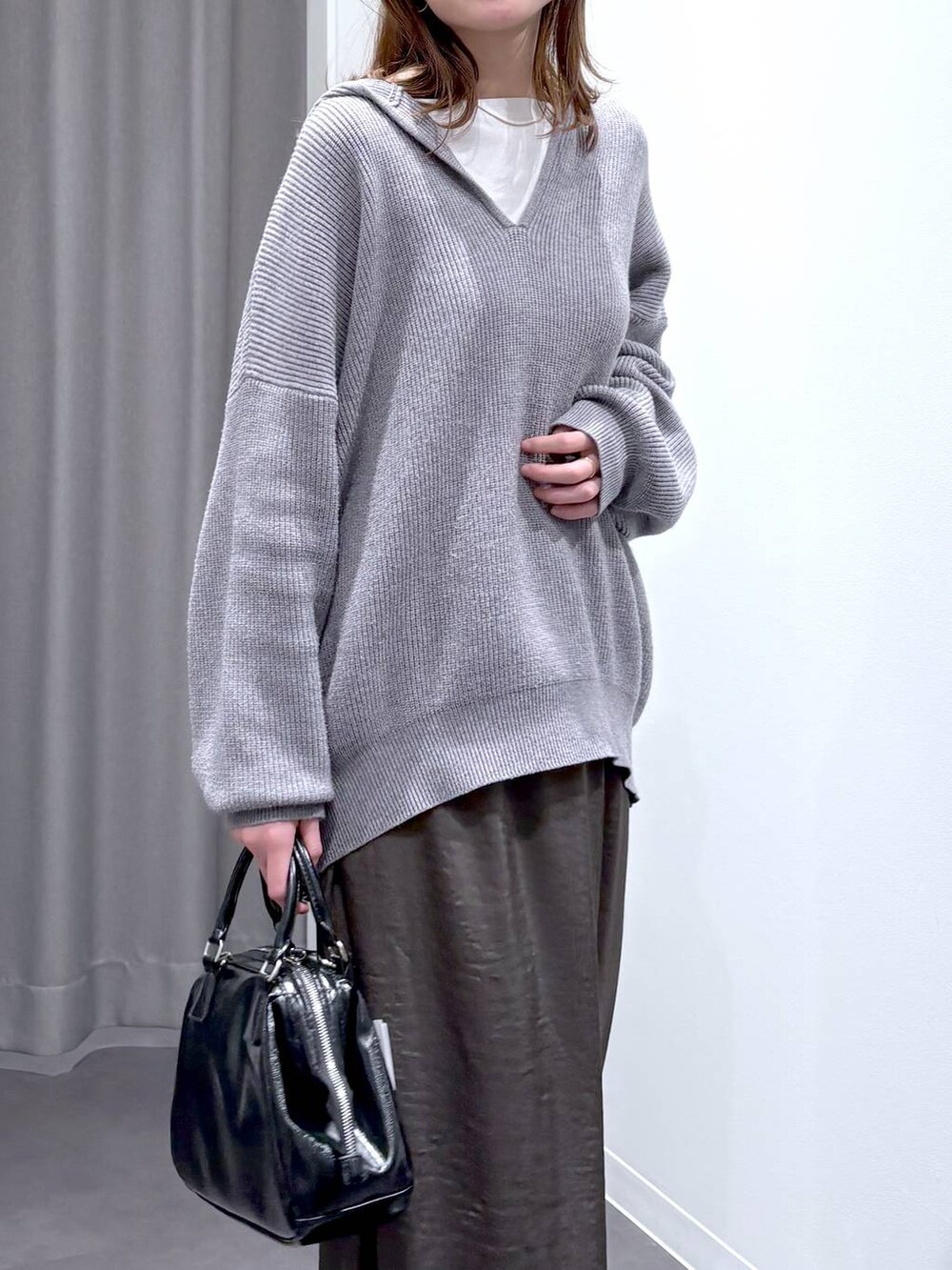 グレー系のスカート、グレー系のニット/セーター、ブラック系のショルダーバッグを着用したレディースの秋コーディネートの5枚目の写真