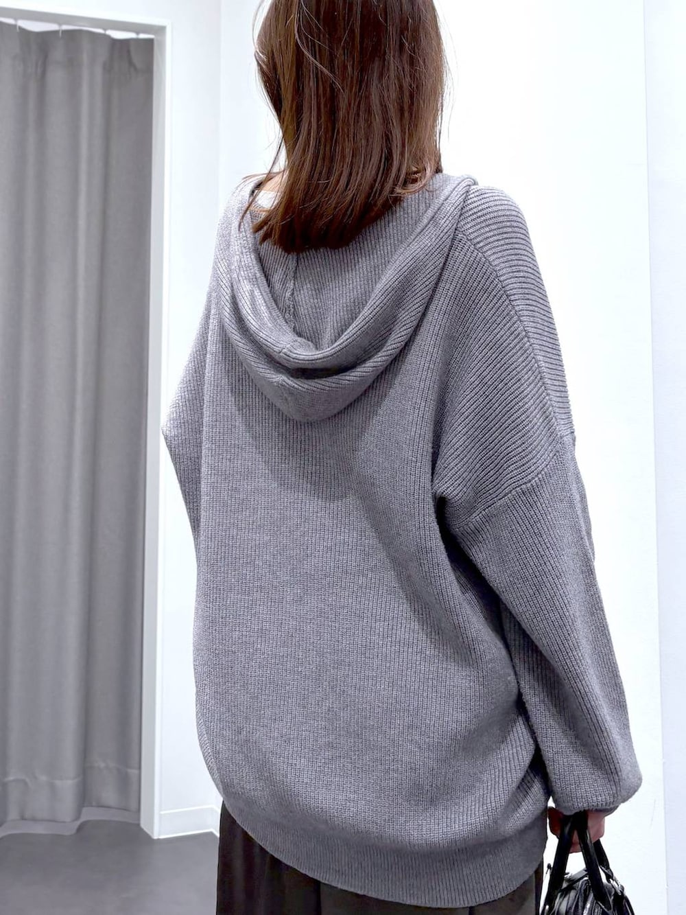 グレー系のスカート、グレー系のニット/セーター、ブラック系のショルダーバッグを着用したレディースの秋コーディネートの7枚目の写真